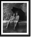 Historic Framed Print, [2 children on fountain wall, under umbrella in rain], 17-7/8" x 21-7/8"